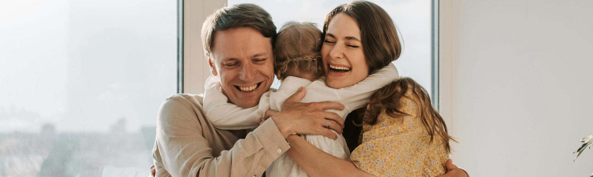 A joyful family hugging tightly near a window, radiating warmth and togetherness.