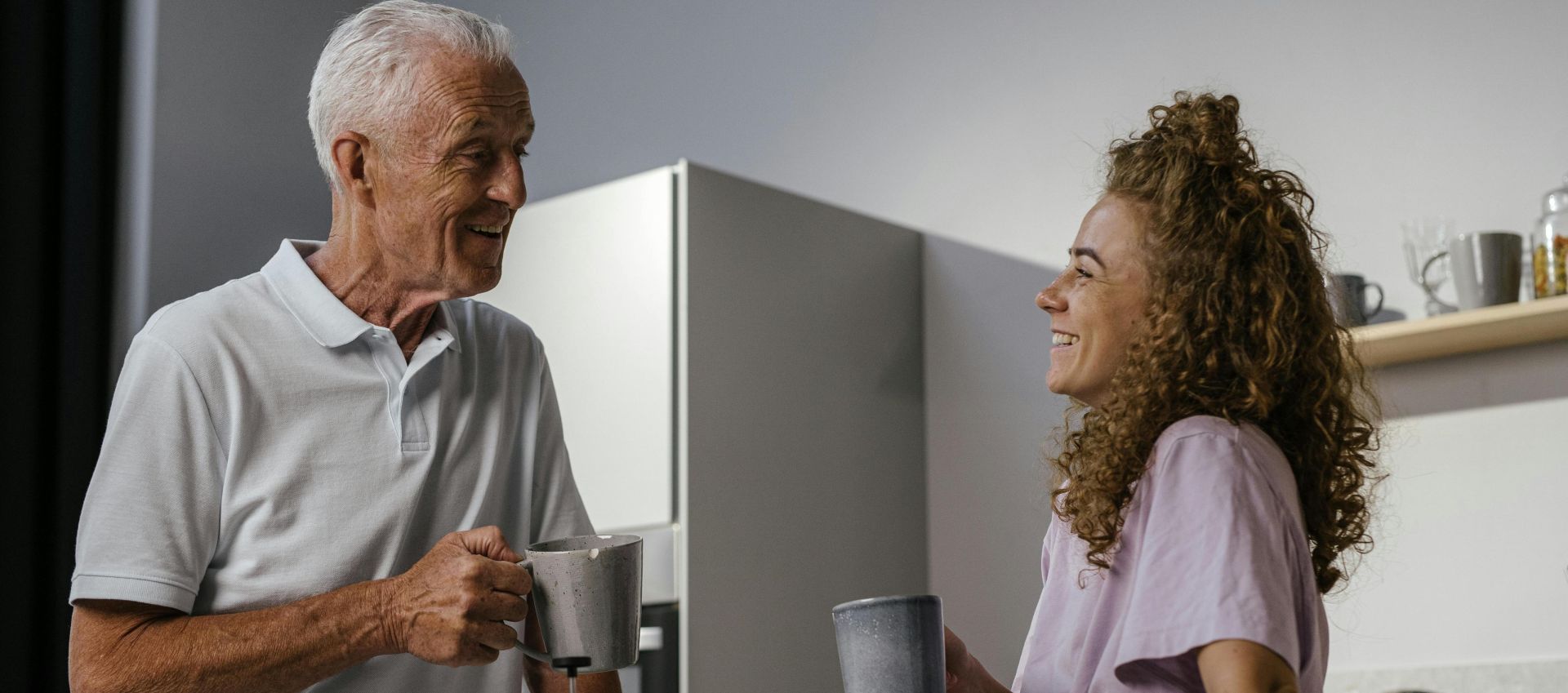 A joyful moment of a grandfather and granddaughter enjoying coffee in a modern kitchen.