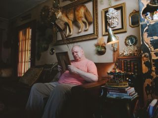 An elderly man in a nostalgic living room, reflecting on memories with a framed photo.